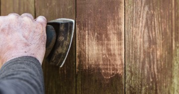 Schreiner beim Abschleifen von altem Holz mit einem Deltaschleifer